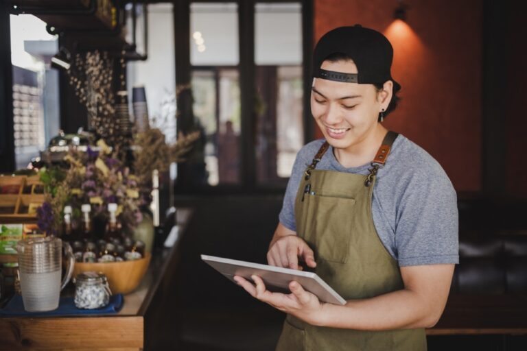 Asian man barista holding tablet for checking order from customer on coffee cafe