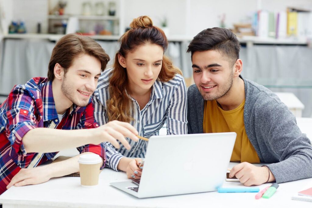 College students brainstorming career development ideas in front of laptop computer