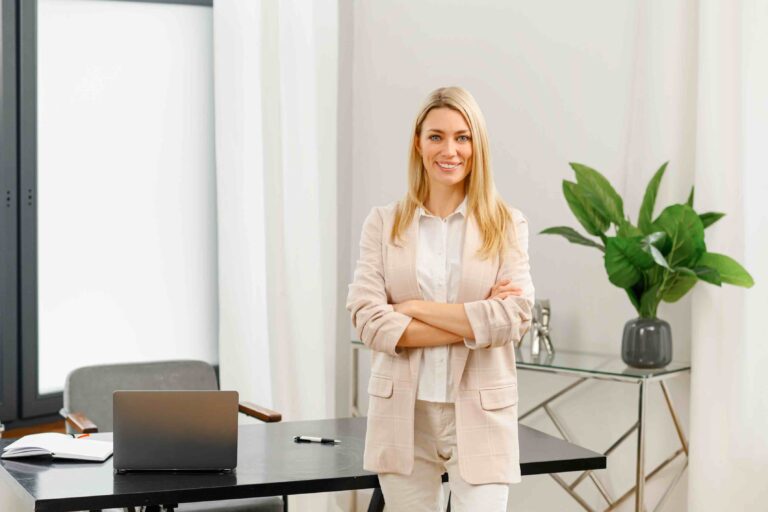 Confident female employee in front of her desk dressed in business professional attire