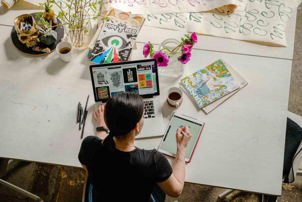 Creative person working on her laptop while scetching ideas on tablet