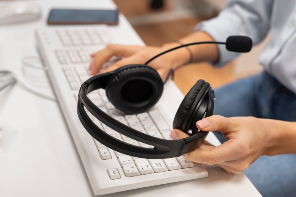 Customer service representative at work holding her headset and typing on keyboard