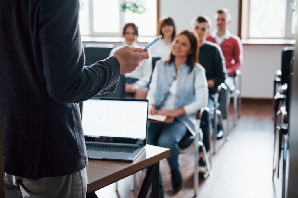 Group of high school students in classroom with a teacher in the foreground