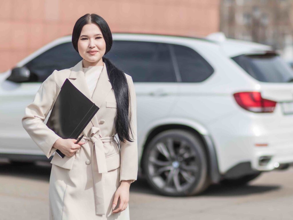 Highly professional executive assistant outside in front of car holding folder