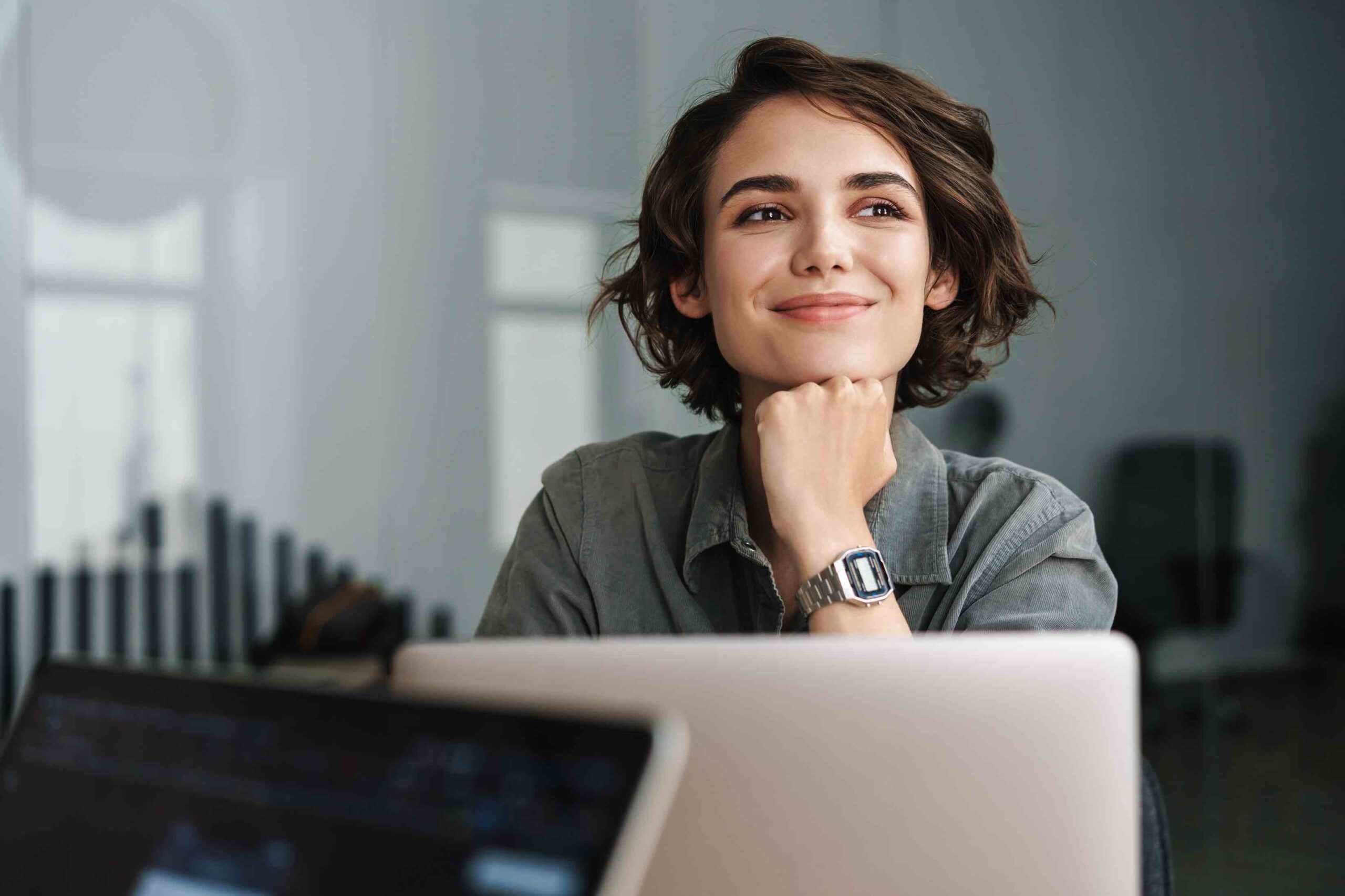 Image of young beautiful woman smiling while working with laptop in office