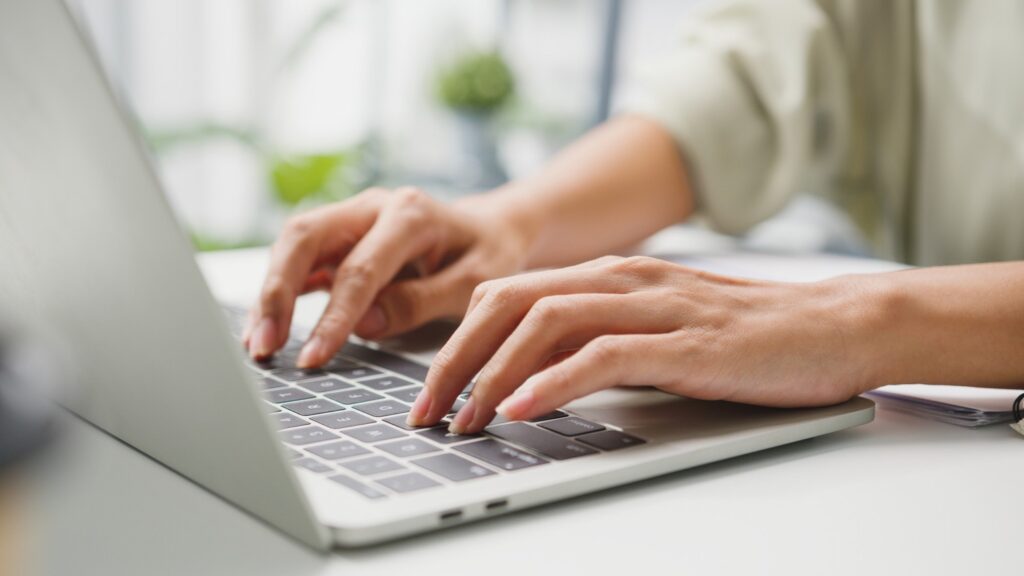 Job applicant who is typing a career change cover letter on her laptop