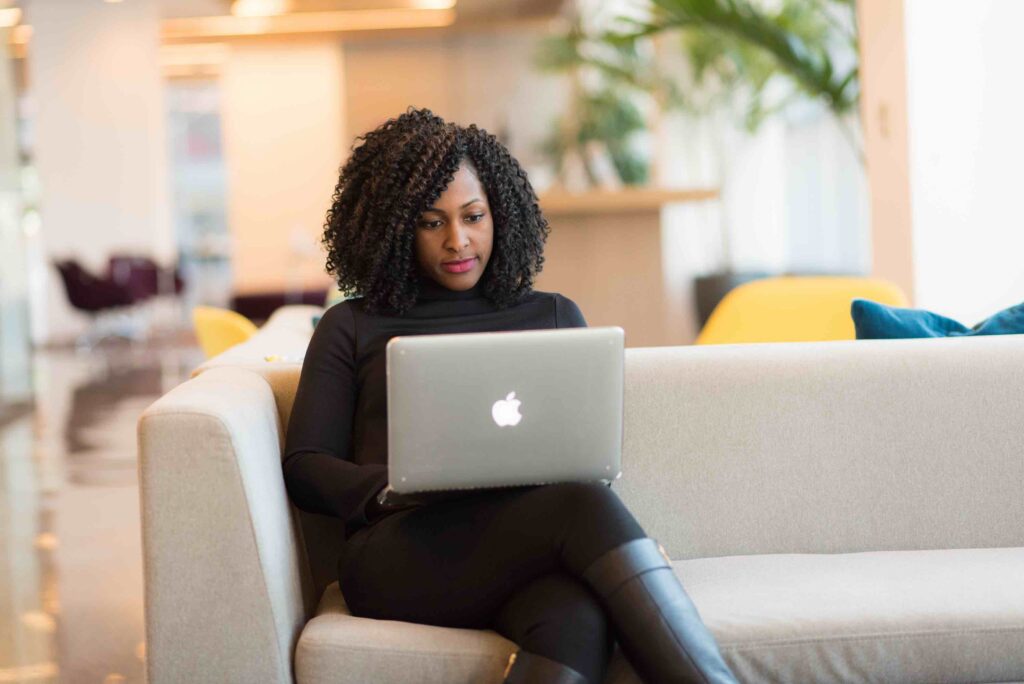 Job seeker sitting on couch drafting a cover letter on her laptop