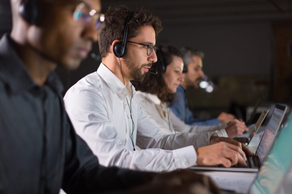 Male customer service representative next to his colleagues taking phone calls