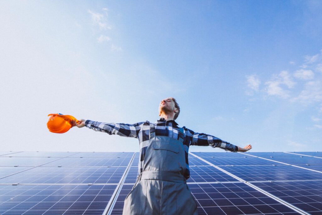 Male worker who loves his work environment in a field with solar panels