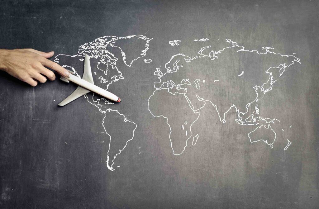 Miniature plane and hand of person over drawn world map