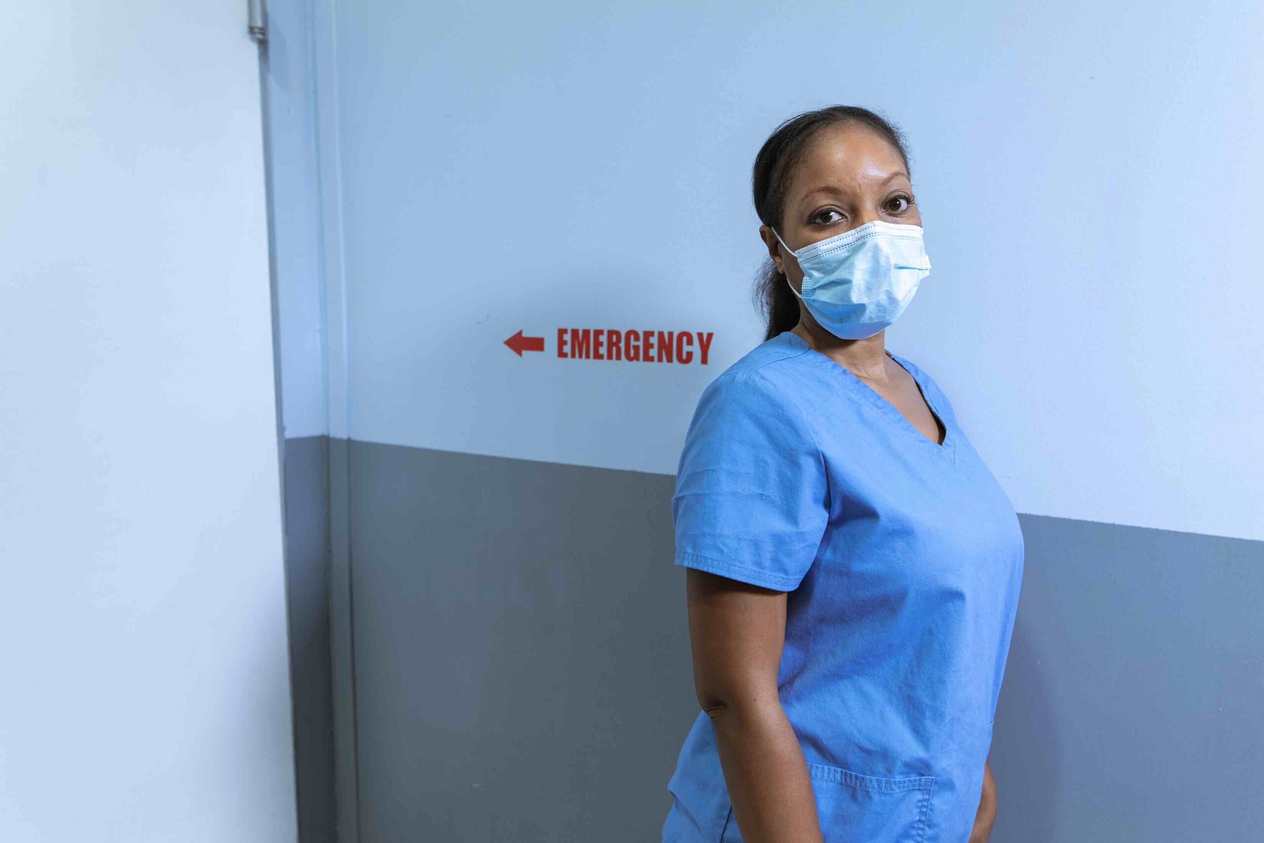 Nurse practitioner with mask in front of emergency room