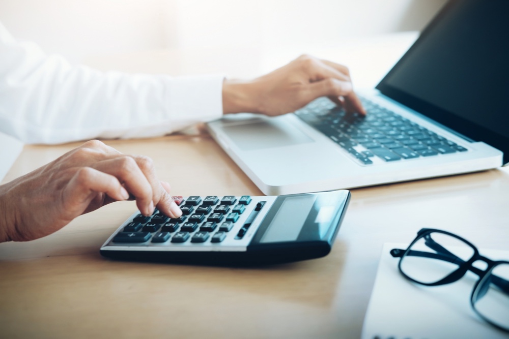 Person calculating a reasonable salary in front of a laptop with a calculator