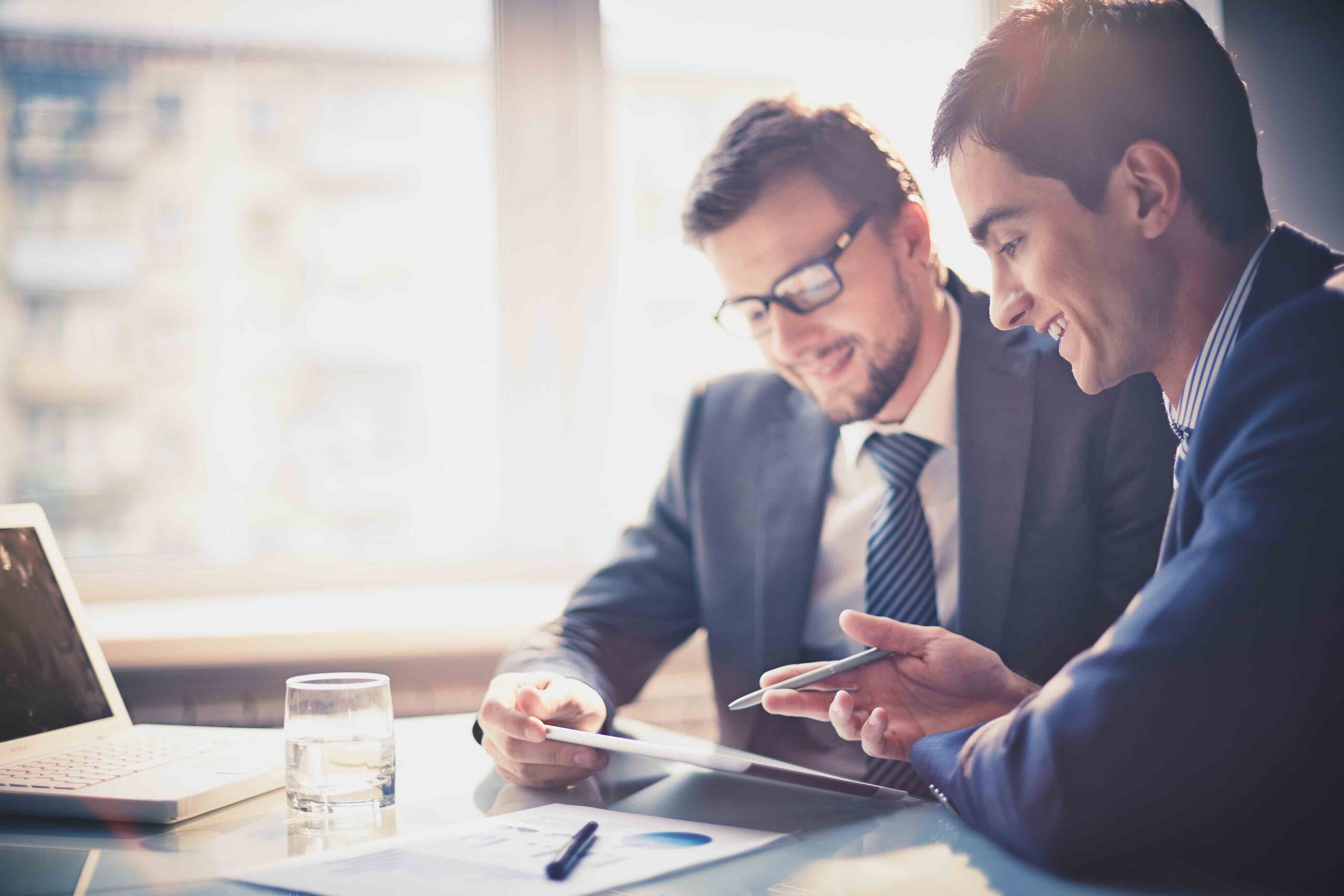 Picture of two young businessmen with touchpad at meeting