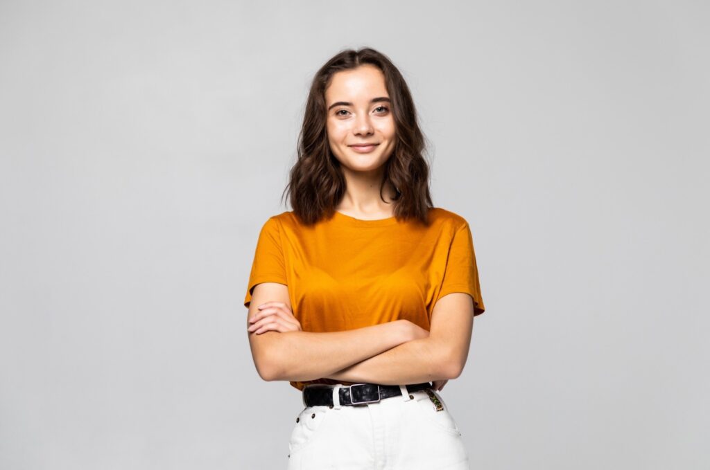 Portrait of beautiful young woman standing on grey wall