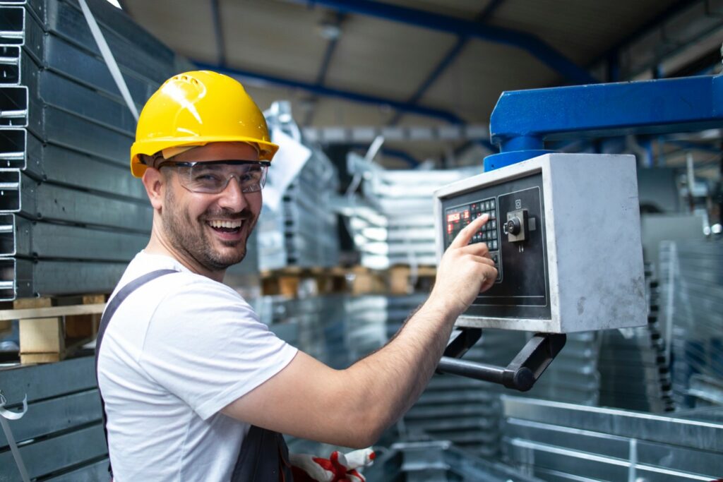 Factory worker operating industrial machine and setting parameters on the computer