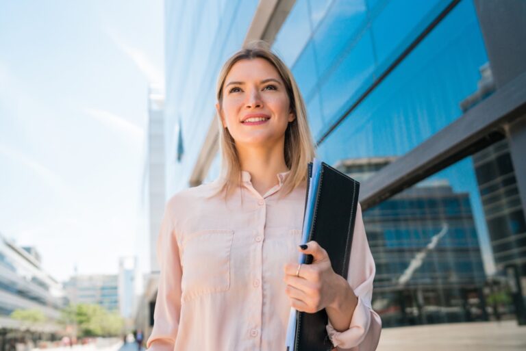 Portrait of young business woman standing in front of office building