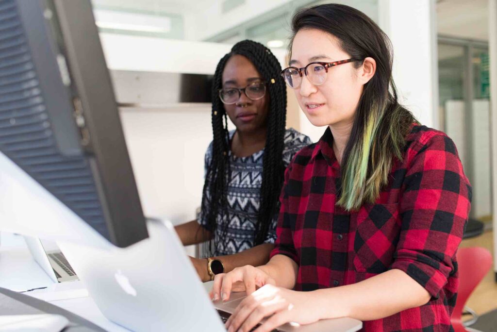 Senior software engineer showing something to a teammate on the computer