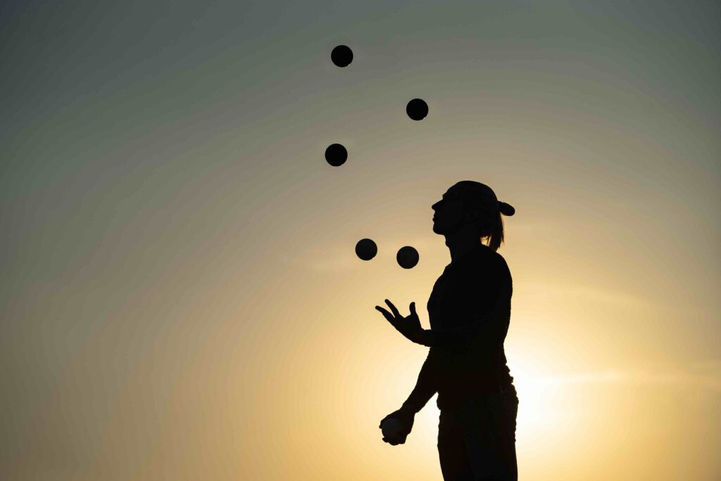 Silhouette of a man juggling with five balls at sunset