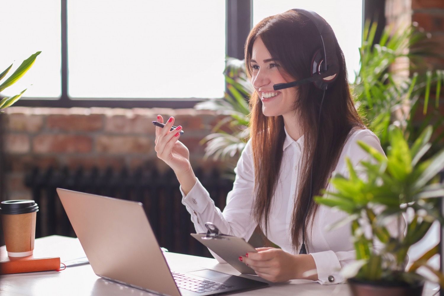 Smiling female customer service worker in front of laptop with headset