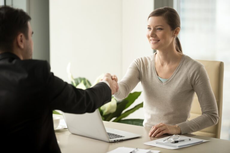 Smiling sales manager shaking hands with client