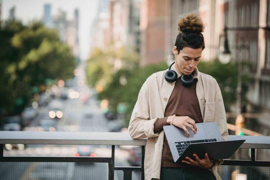 Software developer typing something on his laptop outdoors