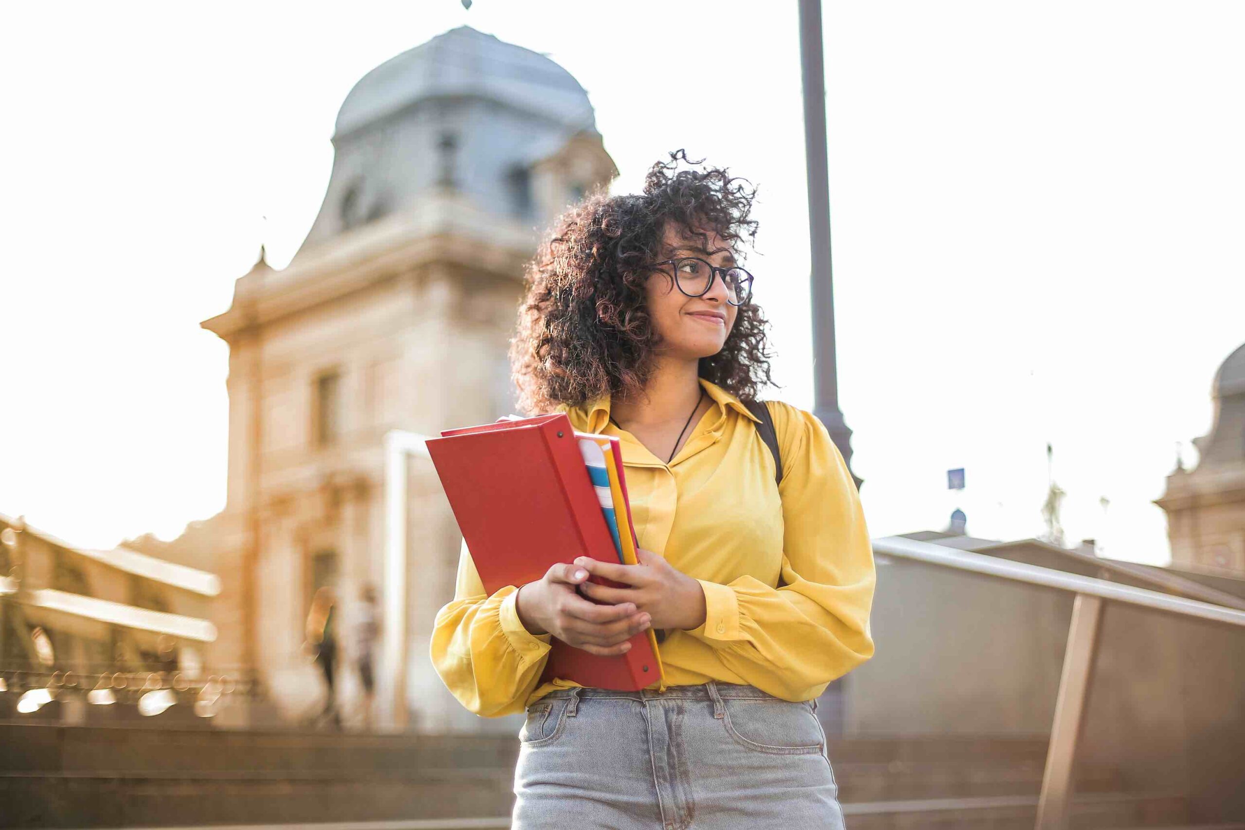 Student in front of university with books