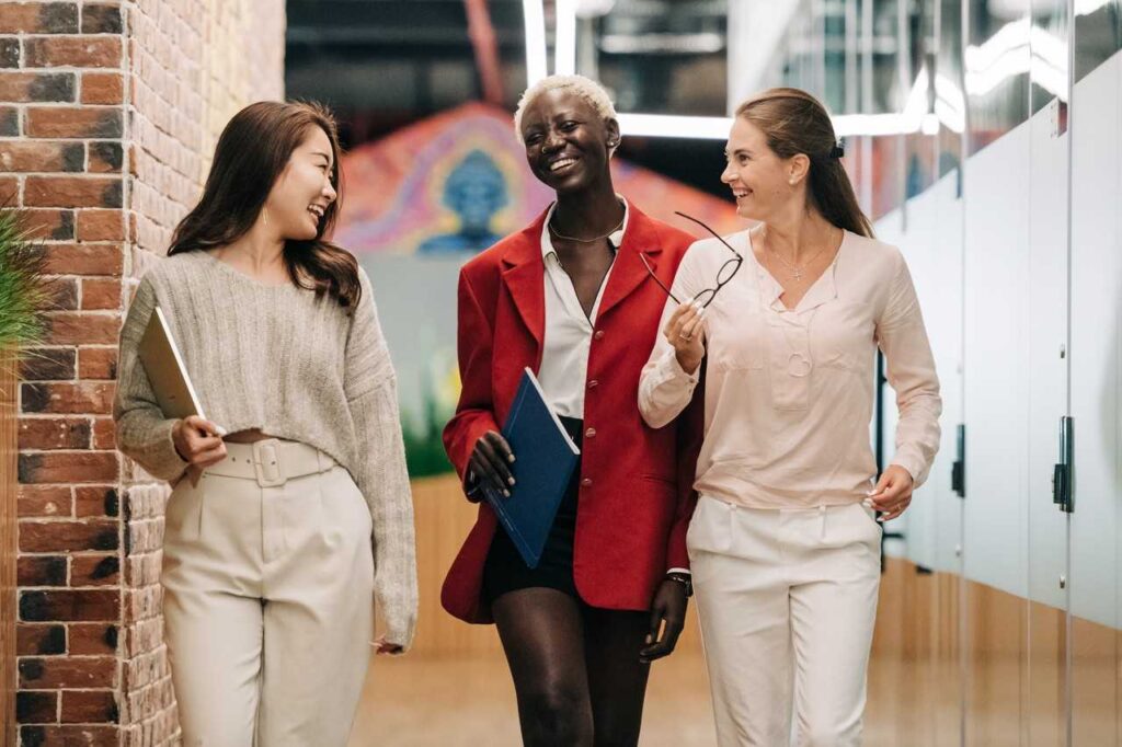 Three female coworkers networking while walking through the office