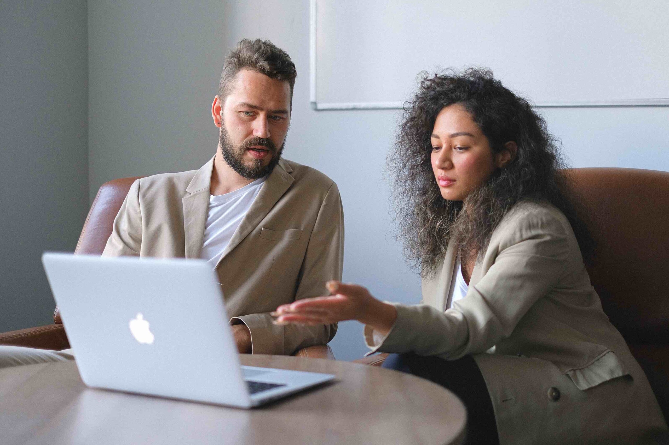 Two project managers working together, looking at something on the laptop and discussing