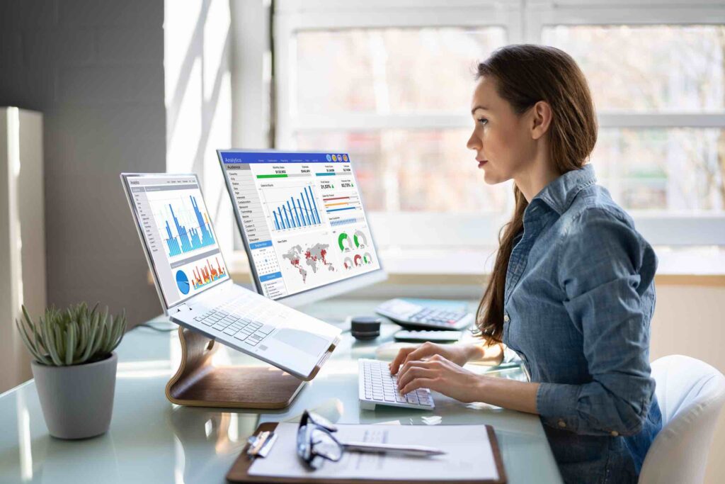 Female analytics manager at work typing in data sitting in front of her laptop