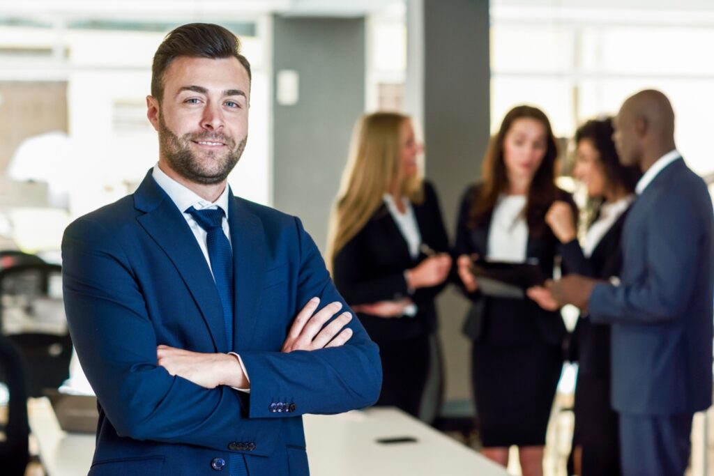 An effective manager with arms crossed in front of his team members