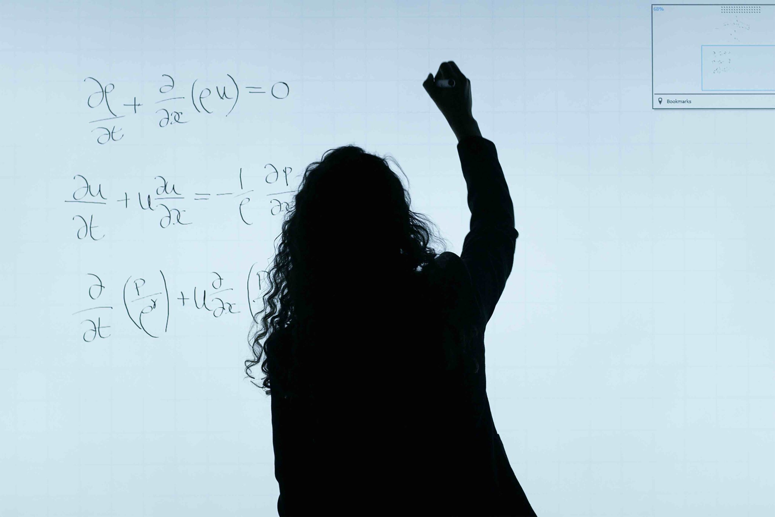 View of a female teacher from behind writing on the whiteboard
