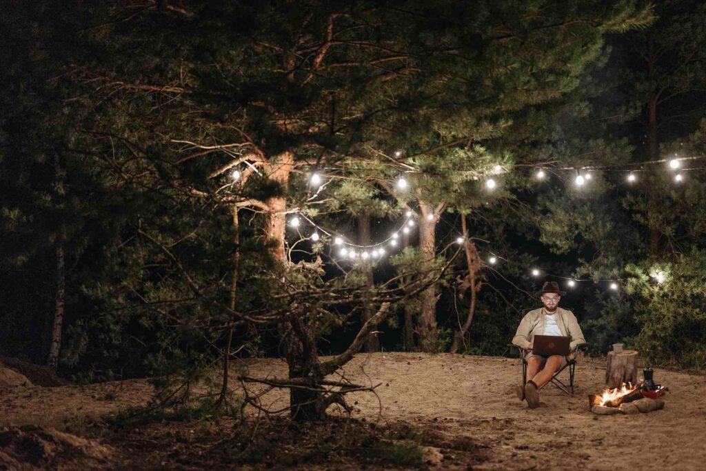 Writer at his laptop outdoors by a cozy campfire