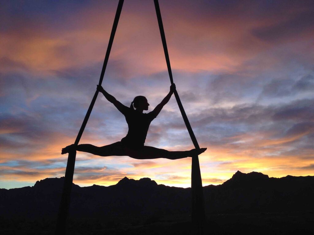 Yoga instructor doing aerial yoga during sunset outdoors