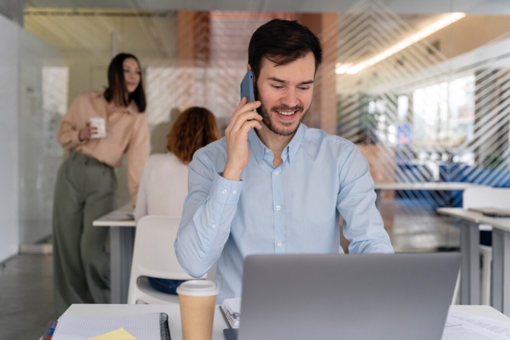 Administrative clerk working at laptop while on phone