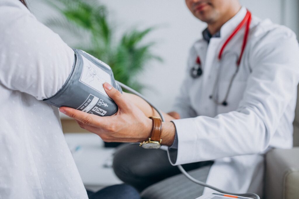 Young male medical assistant with patient measuring blood pressure