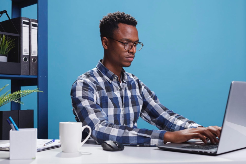 Young marketing manager typing on his laptop in office