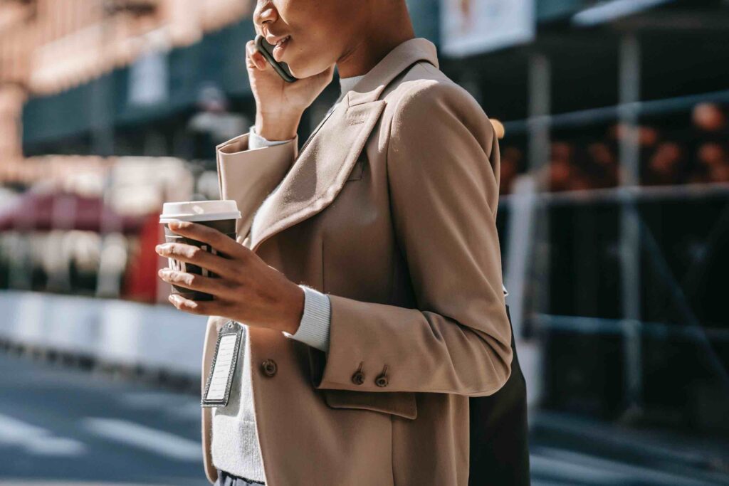 Young sales manager outside office with coffee cup talking to a customer on the phone