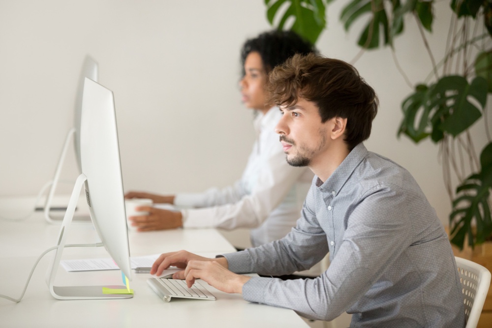 Young serious employee focused on computer work in office