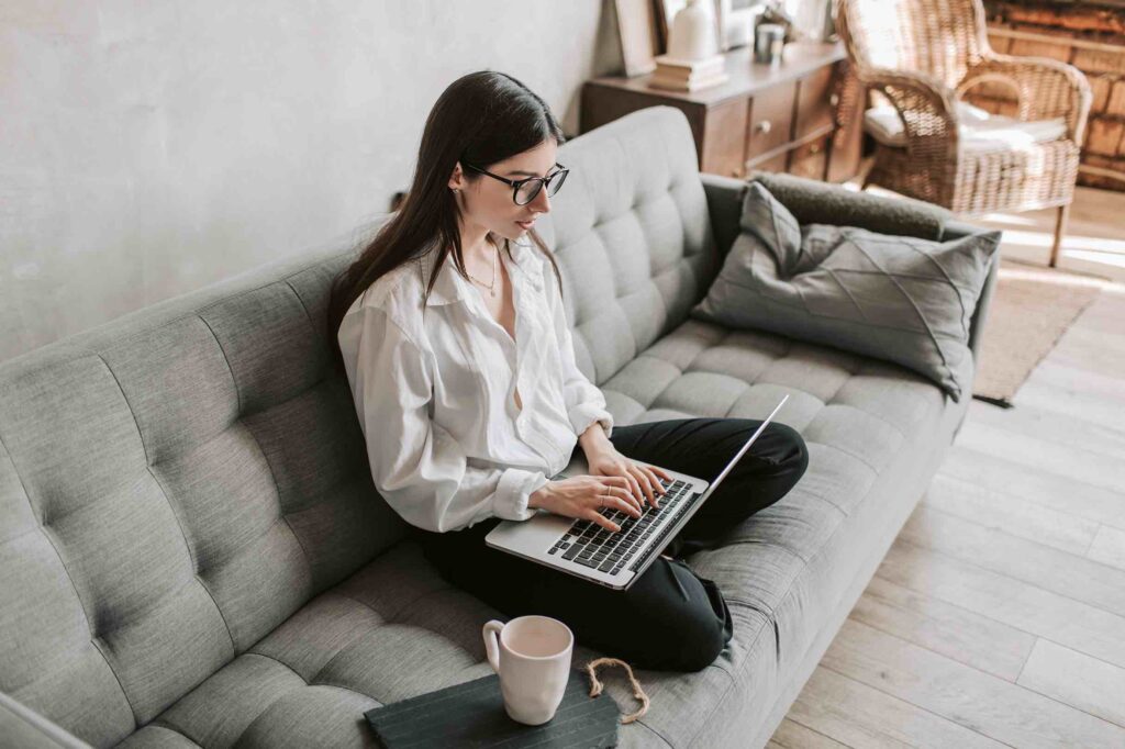 Young software engineer sitting on couch working on her resume