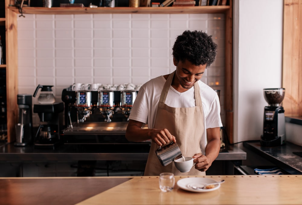 smiling barista making coffee in restaurant or coffee shop