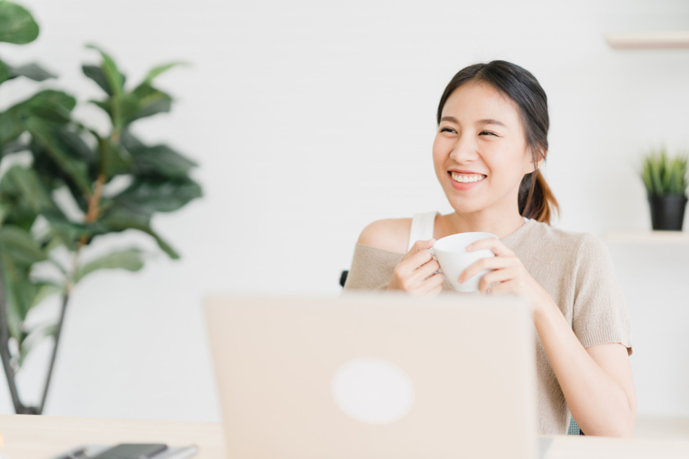 Aspiring young data entry clerk drinking coffee in front of laptop about to draft her data entry resume