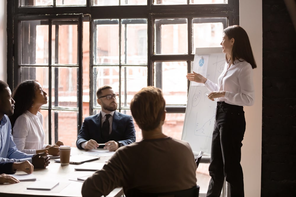 young entrepreneurs sit at the table and listen intently to a young female entrepreneur