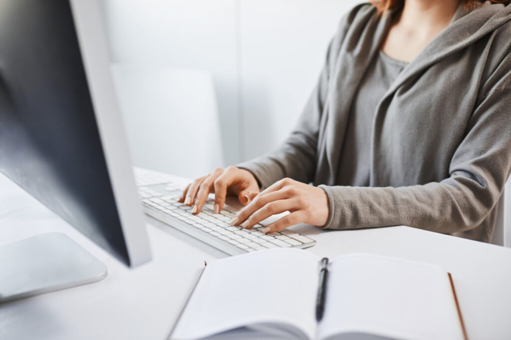 Female transcroptionist typing on keyboard, sitting in front of computer monitor