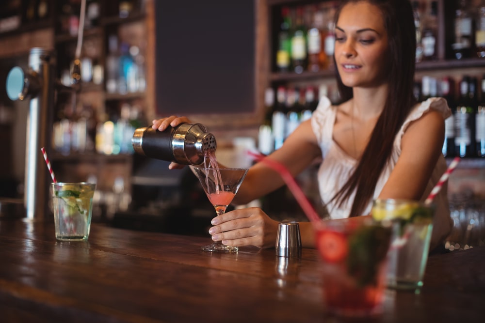 young female bartender serving a cocktail