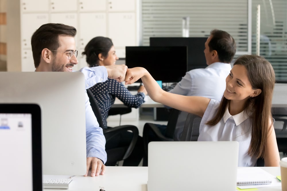 friendly colleagues give each other a fist greeting at the workplace