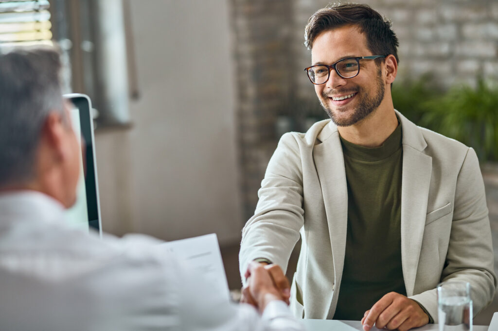 Happy male job candidate handshaking with manager after successful job interview