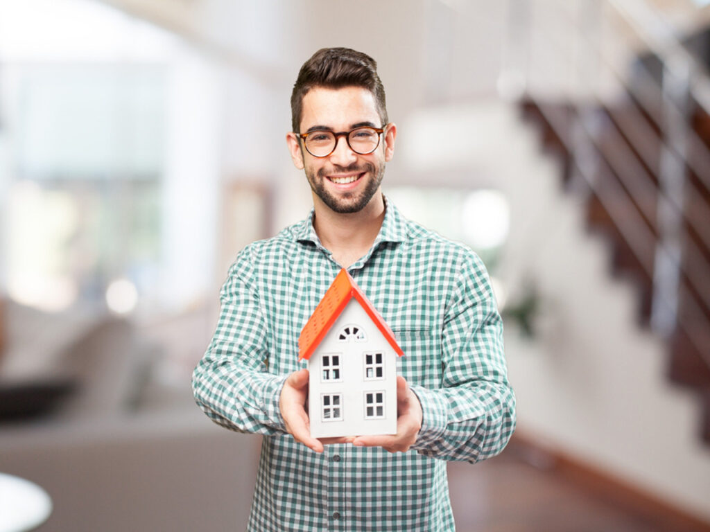 Happy real estate agent holding a tiny house