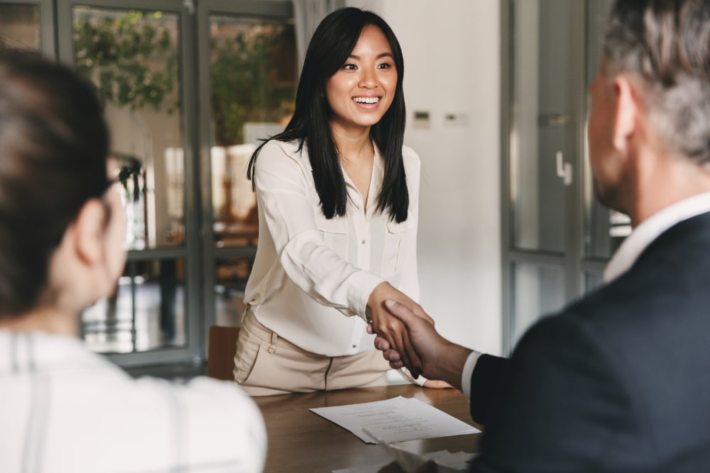 two people are shaking hands at the beginning of an job interview