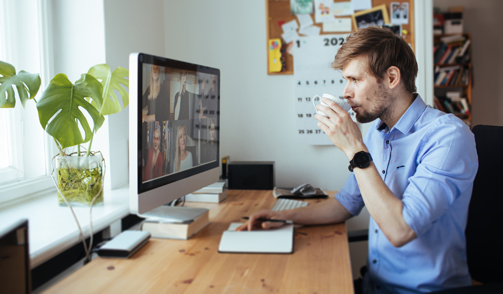 man looking at mac while drinking coffee