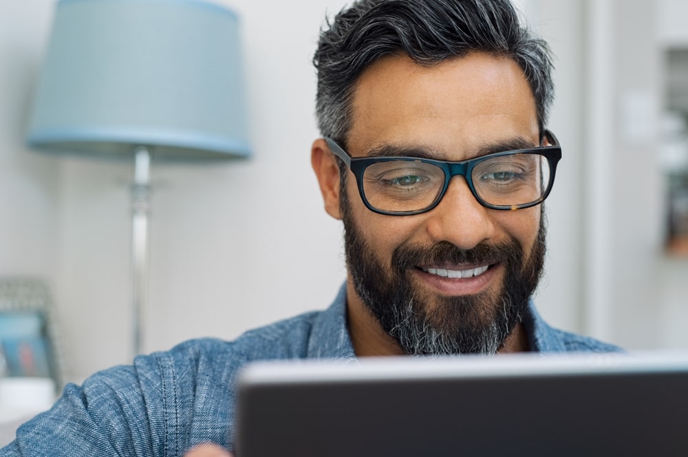 middle-aged man looks at his ipad with a smile