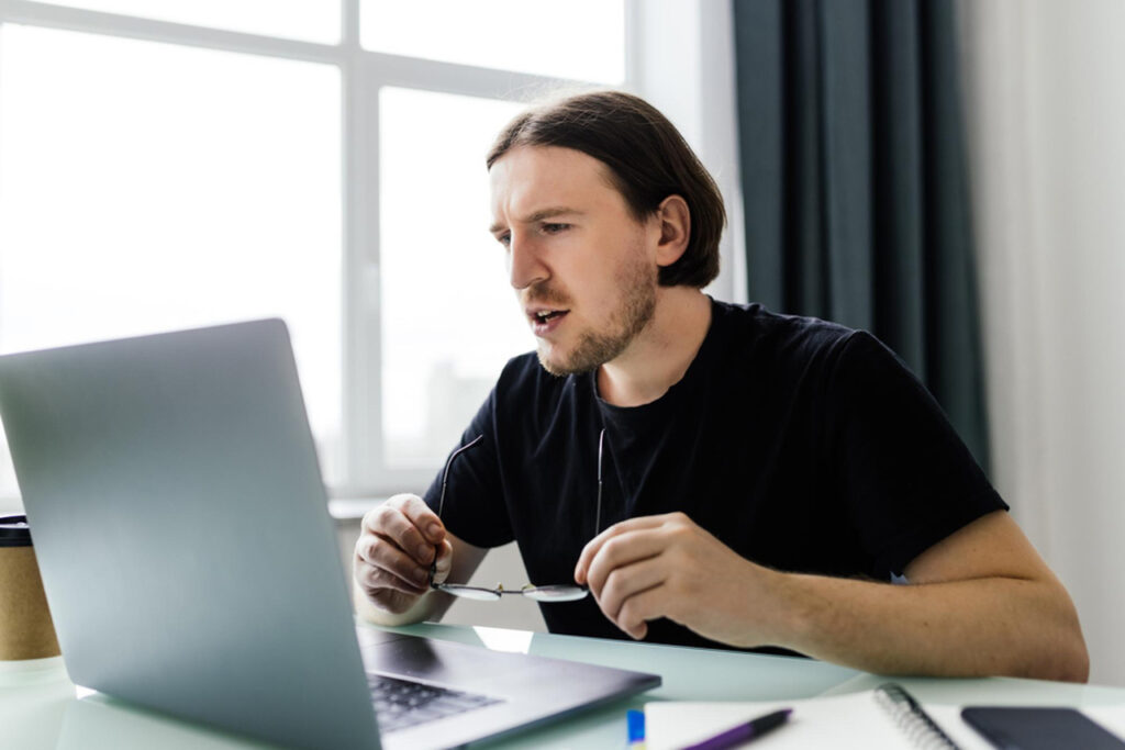 Relaxed male businessperson sitting in front of his laptop reviewing the problem statement he just wrote
